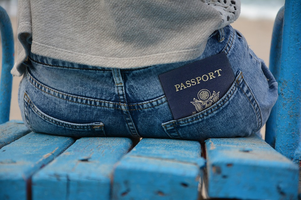 uma mulher sentada em um banco azul com o passaporte guardado no bolso